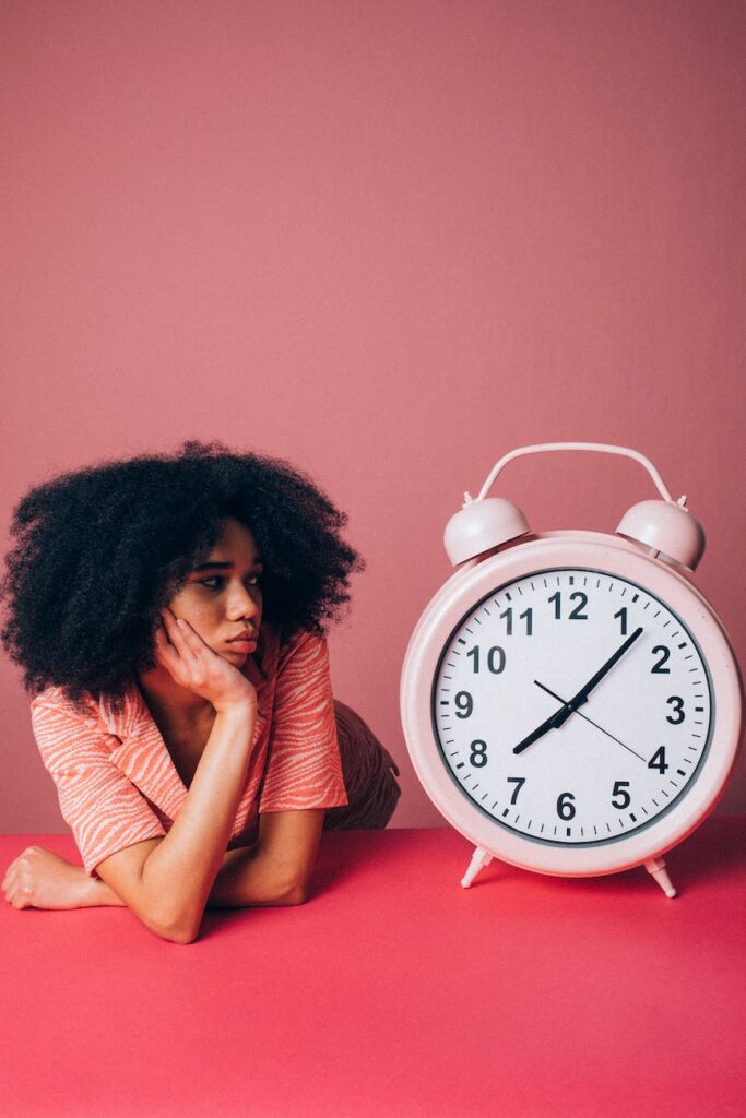 woman looking at a big pink alarm clock, waiting, waiting season, waiting on God